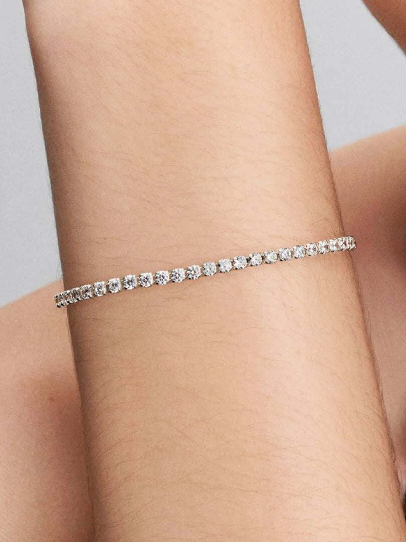 Silver bracelet with small zirconia on a wrist against a neutral background