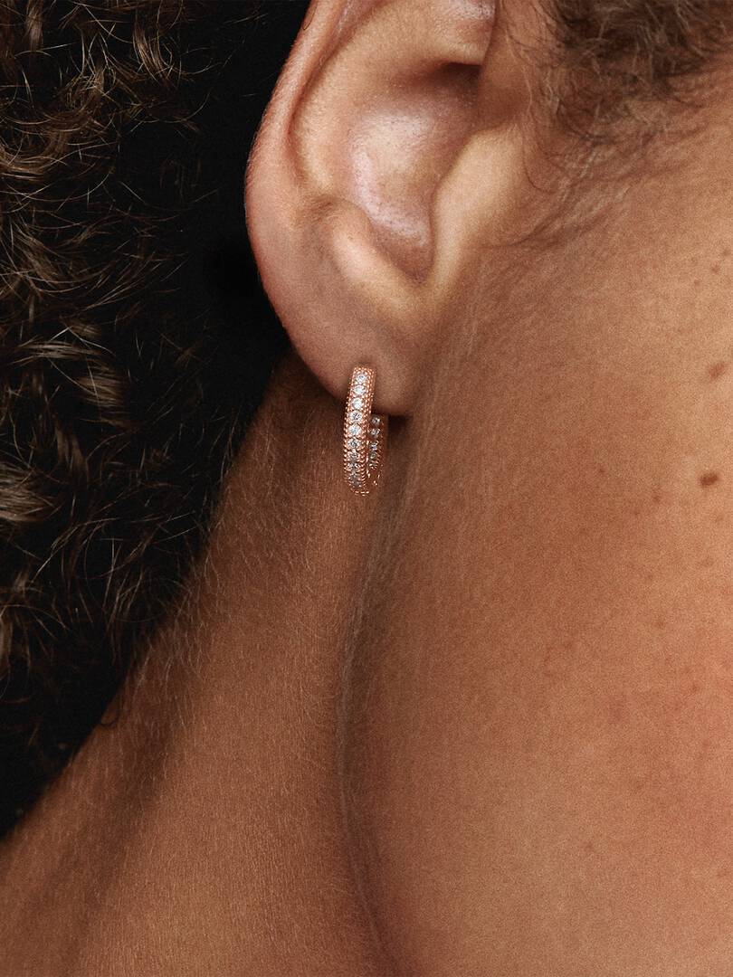 Close-up of an ear wearing a diamond hoop earring.