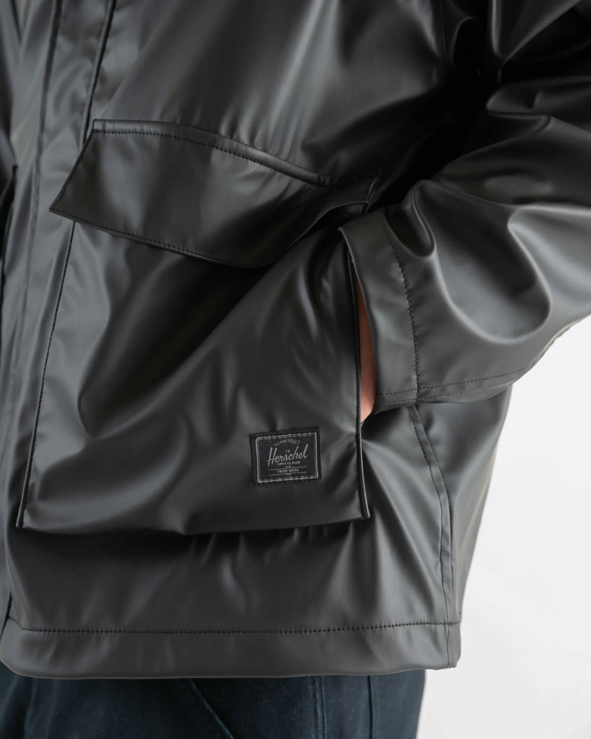 Close-up of a dark gray jacket with a visible brand logo on a light background
