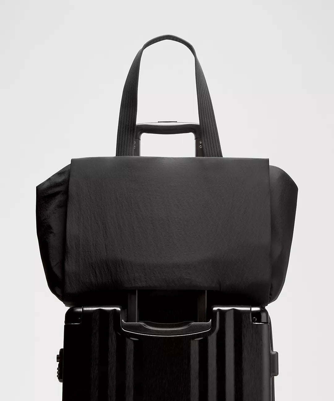 Black backpack on top of a suitcase against a light gray background