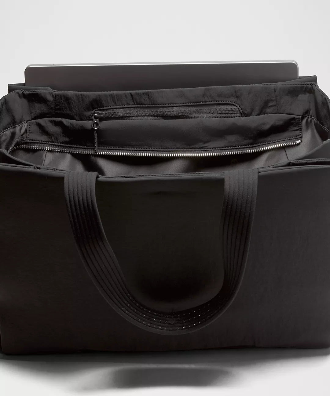 Black duffel bag with a laptop inside on a white background