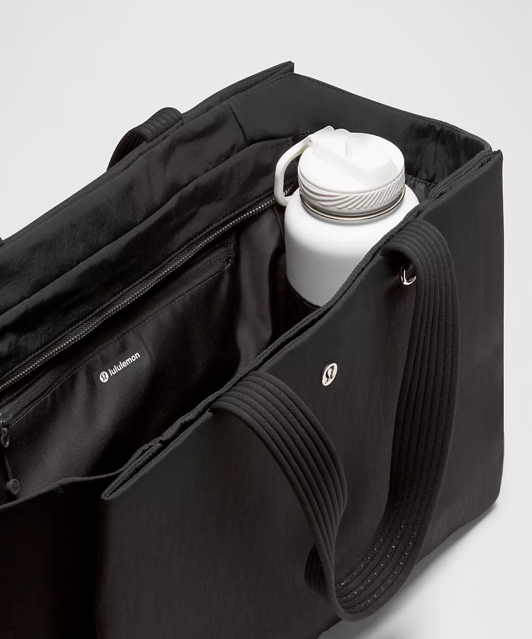 Black bag with a white water bottle inside on a light gray background