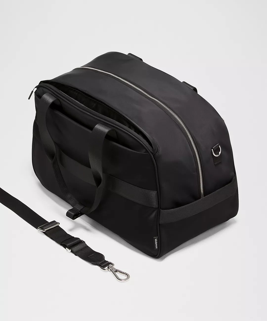 Black duffel bag with a shoulder strap on a light gray background