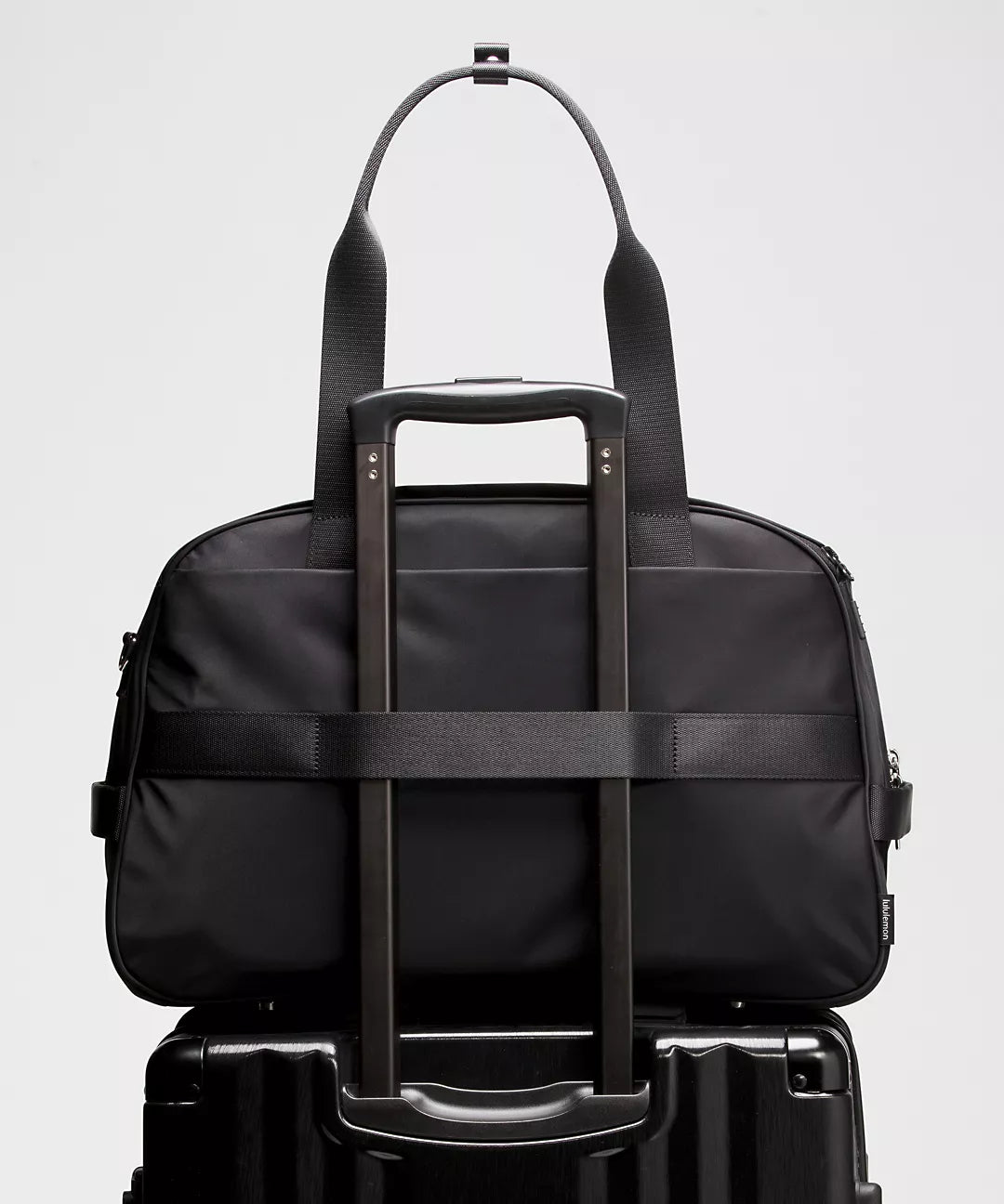 Black travel bag with wheels on a light gray background