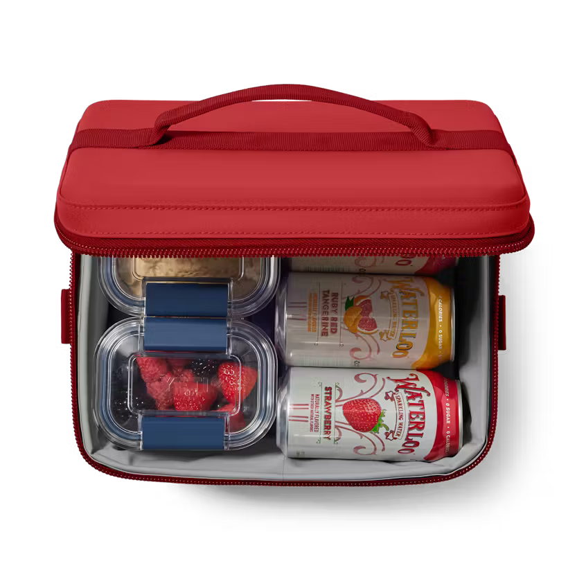Red insulated lunch bag with cans and snacks on a white background