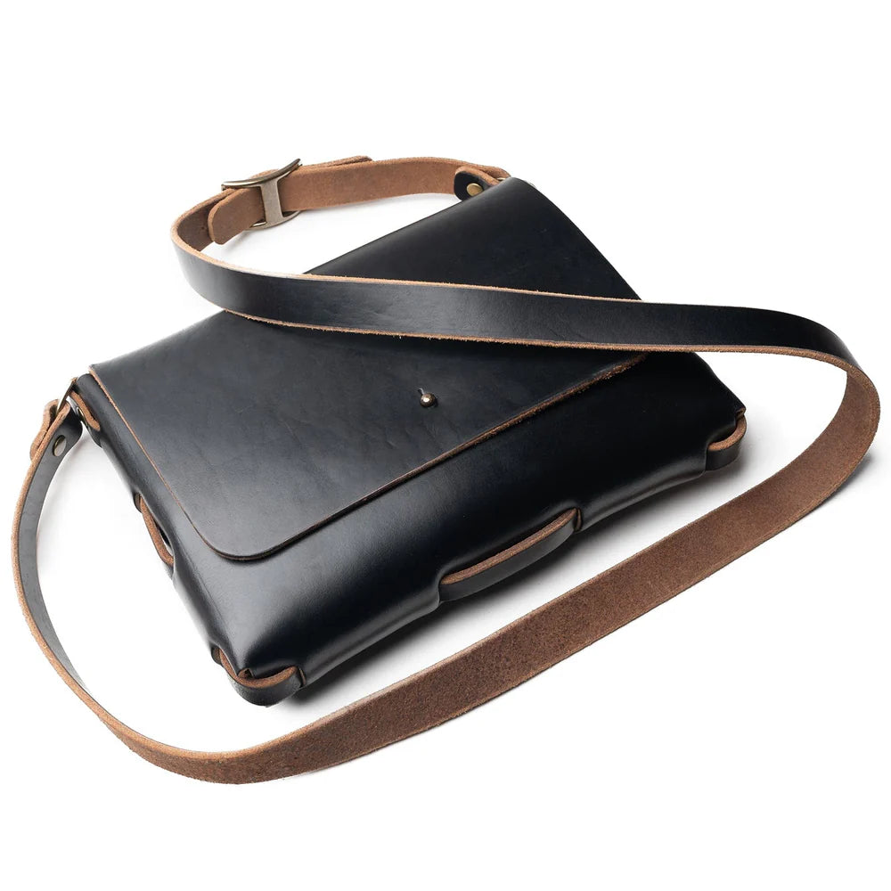 Black leather bag with brown strap on a white background